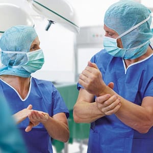 Imagen de apoyo con un par de cirujanos realizando la desinfección prequirúrgica de manos con antisepticos hidrolacohólicos.